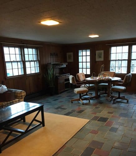 Cozy dining area with wooden walls, large windows, and a round table surrounded by plush chairs, perfect for family gatherings and intimate dinners.
