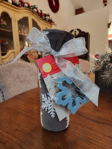 Festive holiday wine bottle decorated with a shiny silver bow, snowflake cookie cutter, perfect for Christmas-themed gifting or seasonal home decor.